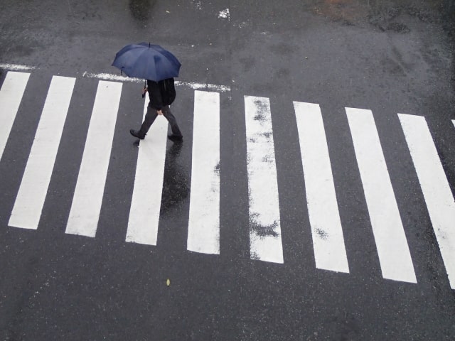 雨の日に傘をさして歩く男性